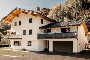 a white house with a balcony and a garage at Ferienappartement Bergliebe in Grossarl