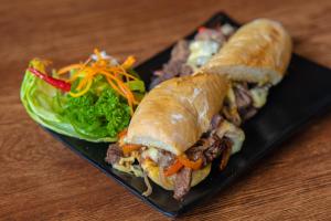 a sandwich and a salad on a black plate at Subic Riviera Hotel & Residences in Kababae