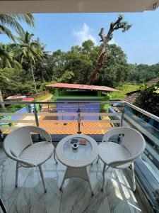 a patio with three chairs and a table on a balcony at Nirvana Homestays in Siolim