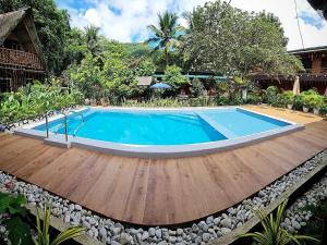 a swimming pool with a wooden deck next to a house at Tinipak Lodge in Tanay