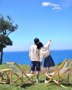 two people standing next to chairs looking at the ocean at 墾丁圓石灘 Kenting Pebble Beach in Fangshan