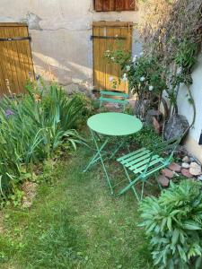 einen grünen Tisch und zwei Stühle in einem Garten in der Unterkunft Joli appartement avec coin jardin in Chalon-sur-Saône