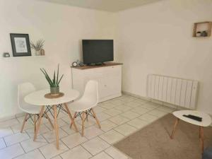 ein Wohnzimmer mit einem Tisch und Stühlen sowie einem TV in der Unterkunft Joli appartement avec coin jardin in Chalon-sur-Saône