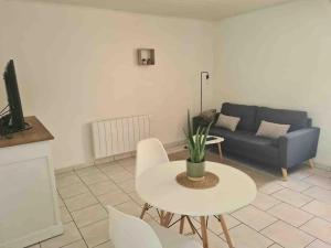 ein Wohnzimmer mit einem Tisch und einem Sofa in der Unterkunft Joli appartement avec coin jardin in Chalon-sur-Saône