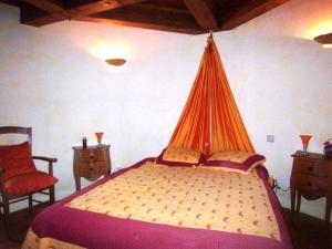 a bedroom with a bed with an orange net on it at Moulin De Rouzé in Castelnaud-de-Gratecambe