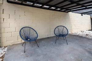 dos sillas azules sentadas junto a una pared de ladrillo en Le Garden B avec salle de sport en Ruan