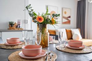 a table with two plates and a vase with flowers at Arctic Golden Sun City Suite in Rovaniemi +5 photos