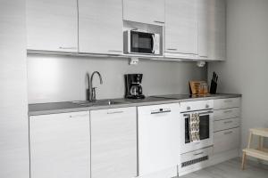 a kitchen with white cabinets and a microwave at Arctic Golden Sun City Suite in Rovaniemi