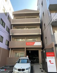 una macchina bianca parcheggiata di fronte a un edificio di Guest House Flora Otemachi/フローラ大手町 a Hiroshima