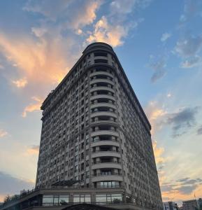 un grand bâtiment avec un ciel nuageux en arrière-plan dans l'établissement Flat Apartments Skopje, à Skopje
