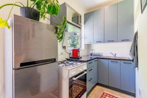 a kitchen with white cabinets and a stove top oven at Cozy 2 bedroom garden cottage in Melville in Johannesburg