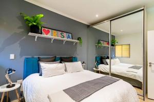 a bedroom with a large bed and a mirror at Cozy 2 bedroom garden cottage in Melville in Johannesburg