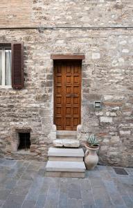 a stone building with a wooden door and a potted plant at Casa Stella appartamento in centro su 3 piani ingresso indipendente in Gubbio