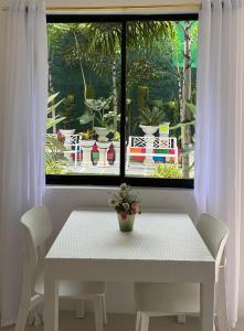 uma mesa branca e cadeiras num quarto com uma janela em The Veehive Guesthouse em Cebu