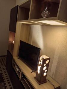 Cette chambre dispose d'une télévision et d'une table avec une lampe. dans l'établissement Les Acacias - Maison Orly, à Orly