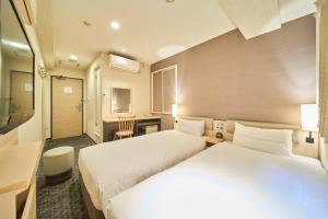 a hotel room with two beds and a bathroom at Via inn Kyoto Shijomuromachi in Kyoto