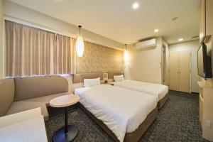 a hotel room with two beds and a couch at Via inn Kyoto Shijomuromachi in Kyoto
