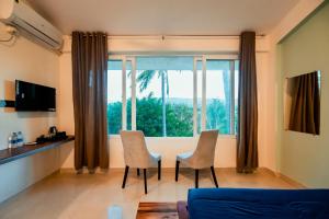 a living room with a table and chairs and a large window at Commune18 Resort Chikmagalur in Chikmagalūr