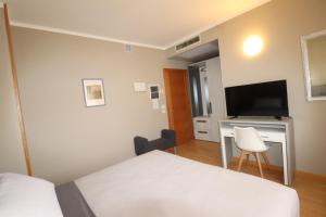 a hotel room with a bed and a desk with a television at Hotel Rio Umbertide in Umbertide