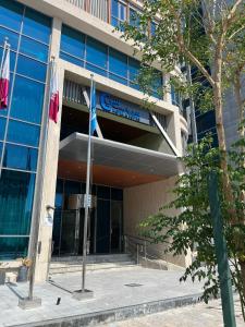 um edifício de escritórios com uma bandeira à sua frente em C - Hotel and Suites Doha em Doha