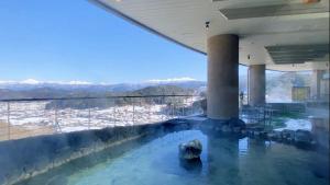a swimming pool in a building with a view of the mountains at Hotel Associa Takayama Resort in Takayama