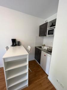 a small kitchen with a white counter and a stove at Acajou, Studio avec terrasse et parking privé in Caen +3 photos