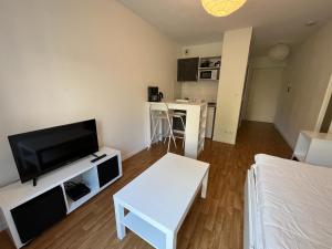 a living room with a flat screen tv and a couch at Acajou YourHostHelper in Caen