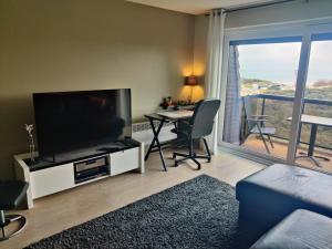 a living room with a flat screen tv and a table with chairs at Appartement met zeezicht, 2 balkons N & Z met prachtig verzicht en een gratis parkeerplaats in Koksijde