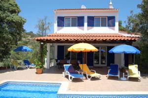 a house with chairs and umbrellas next to a swimming pool at Casa dos Amigos-cottage for 6 persons in Estói