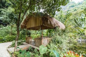 a hut with two chairs under an umbrella at Thung Sen Tam Coc Chalets in Ninh Binh