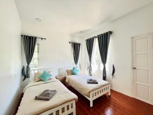 zwei Betten in einem Zimmer mit zwei Fenstern in der Unterkunft บ้านพักดีมีทรัพย์ Baan PakDee Meesub in Uthai Thani