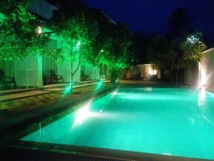 uma piscina à noite com luzes verdes em The Ritz Hikkaduwa em Hikkaduwa