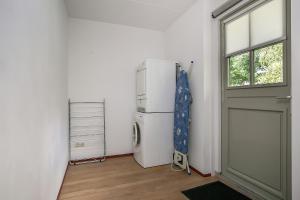 een kamer met een koelkast, een raam en een deur bij De Appelhoeve in Appelscha
