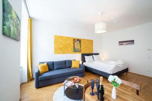 a living room with a blue couch and a bed at Sunny and Stylish - Free Parking - 15 min to Center in Vienna