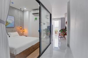 a bedroom with a white bed and a glass doorway at MTR Apartment & Hotel in Da Nang