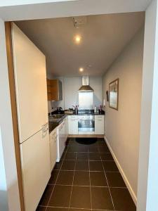 a kitchen with white cabinets and a brown tile floor at The Clayton Charming One Bedroom Apartment in Dublin