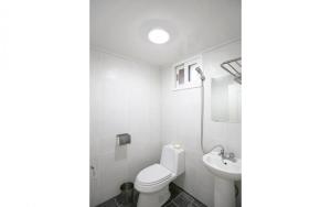 a white bathroom with a toilet and a sink at MO Guesthouse in Jeju