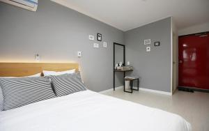 1 dormitorio con 1 cama blanca grande y escritorio en MO Guesthouse en Jeju