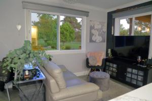 a living room with a white couch and a television at Cottage On The Greens - Studio in Poway
