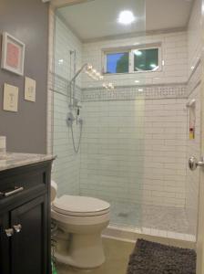 a bathroom with a toilet and a shower with a glass door at Cottage On The Greens - Studio in Poway