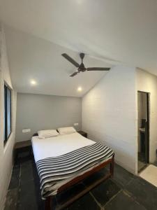 a bedroom with a bed with a ceiling fan at 12 Monks Hostel in Arambol