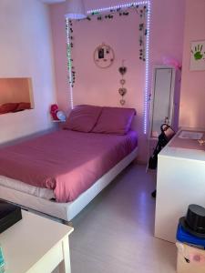 een slaapkamer met een paars bed met verlichting aan de muur bij Angelina in Chabris