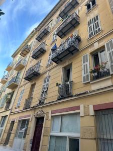 a tall yellow building with windows and balconies at Beau studio au cœur de Nice in Nice