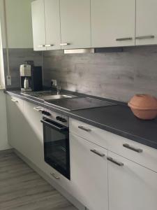 cocina con armarios blancos, fogones y fregadero en Ferienwohnung Fam.Werner, en Wasungen