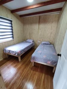 Duas camas num quarto com pisos em madeira em CABAÑA pasos de la playa panguipulli em Panguipulli