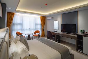 Habitación de hotel con cama, escritorio y TV. en Subic Riviera Hotel & Residences en Kababae