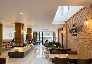 a restaurant with tables and chairs and a brick wall at The Coconut Hotel in Lampang