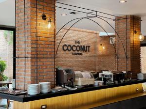 a restaurant with a brick wall and a counter with dishes at The Coconut Hotel in Lampang