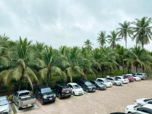 a bunch of cars parked in a parking lot with palm trees at The Coconut Hotel in Lampang