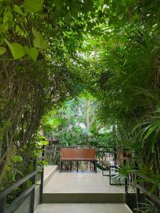 a wooden bench sitting on a walkway with trees at The Coconut Hotel in Lampang
